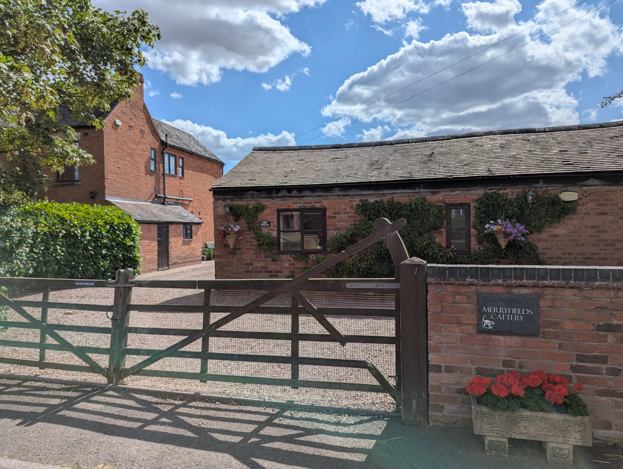 Merryfields farmhouse and cattery behind the entrance gate on a bright country day